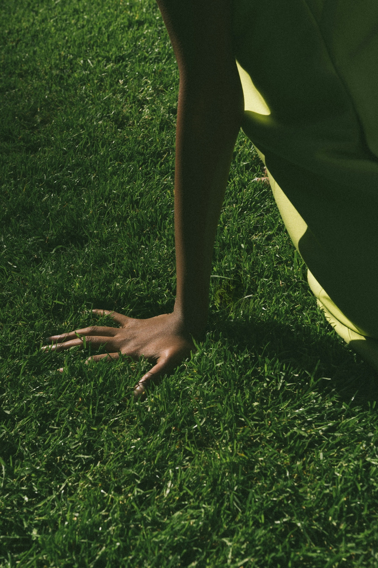 Hand pressing into grass, chartreuse fabric
